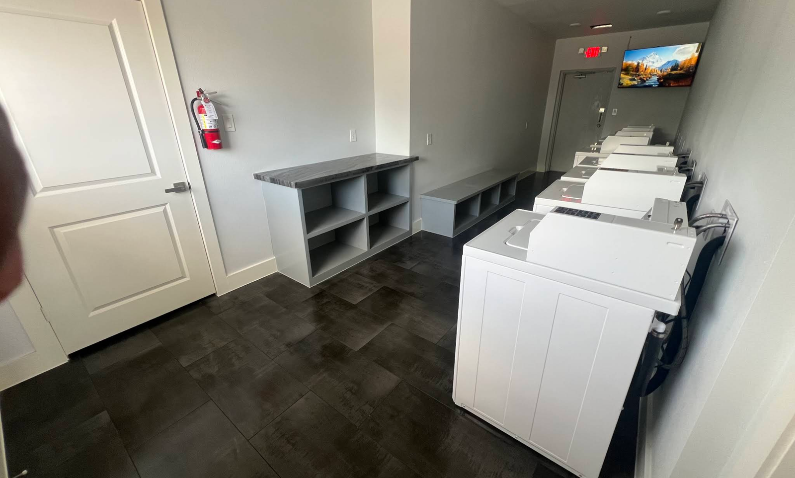 Wide view of the bright laundry room and its row of machines